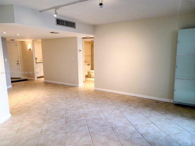 spare room with track lighting, light tile patterned flooring, and visible vents