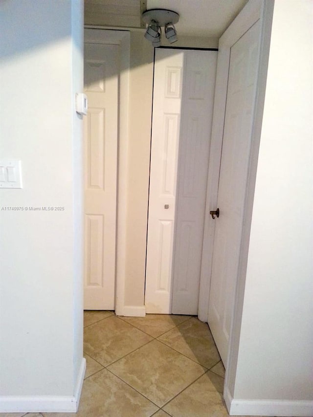 hallway with light tile patterned floors and baseboards