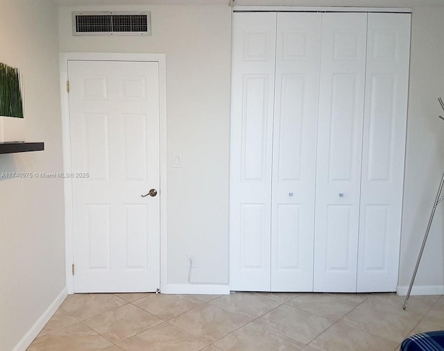 unfurnished bedroom with a closet, light tile patterned flooring, baseboards, and visible vents