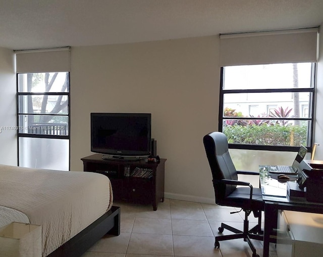 bedroom featuring light tile patterned floors, multiple windows, and baseboards
