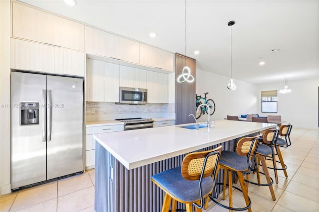 kitchen with sink, a center island with sink, hanging light fixtures, and appliances with stainless steel finishes