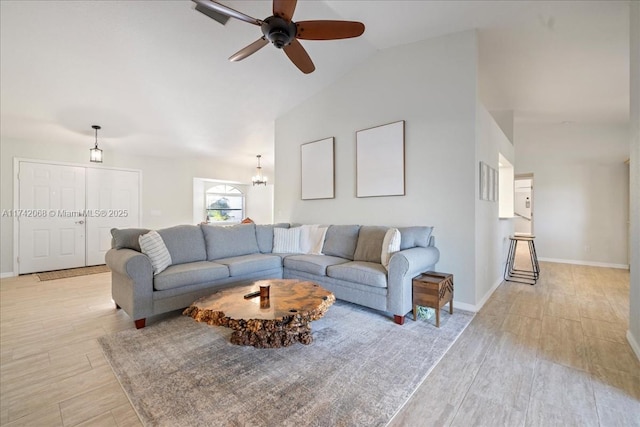 living room with ceiling fan with notable chandelier, high vaulted ceiling, and light hardwood / wood-style flooring