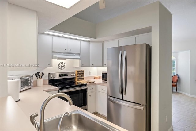 kitchen with appliances with stainless steel finishes, sink, light hardwood / wood-style flooring, and white cabinets