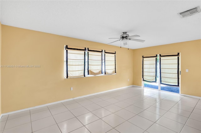 empty room featuring light tile patterned floors, baseboards, visible vents, and a ceiling fan