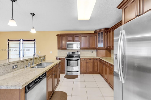 kitchen featuring pendant lighting, stainless steel appliances, glass insert cabinets, light tile patterned flooring, and a sink