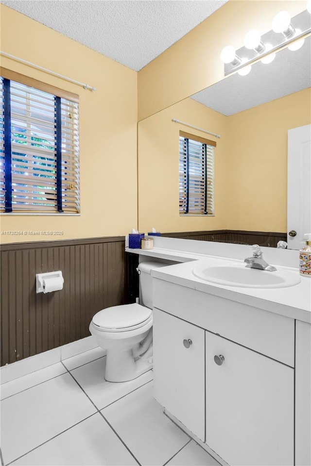 bathroom featuring toilet, a wainscoted wall, tile patterned flooring, a textured ceiling, and vanity