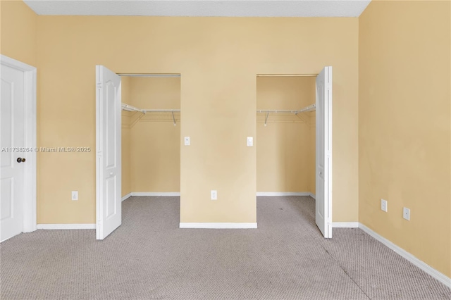 unfurnished bedroom featuring baseboards, a walk in closet, and light colored carpet