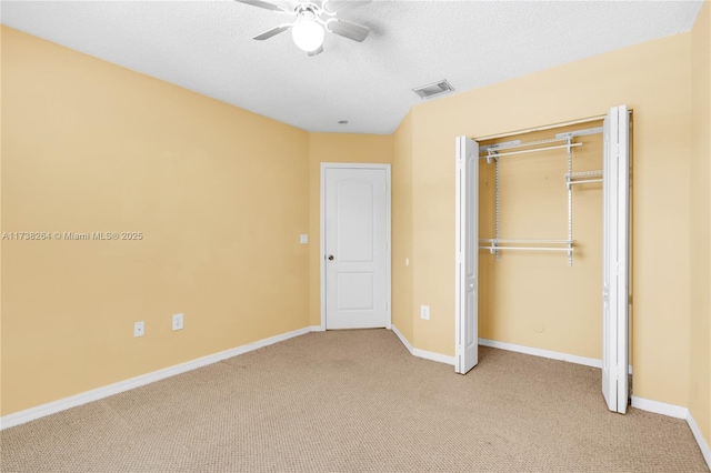 unfurnished bedroom featuring light carpet, baseboards, visible vents, a textured ceiling, and a closet