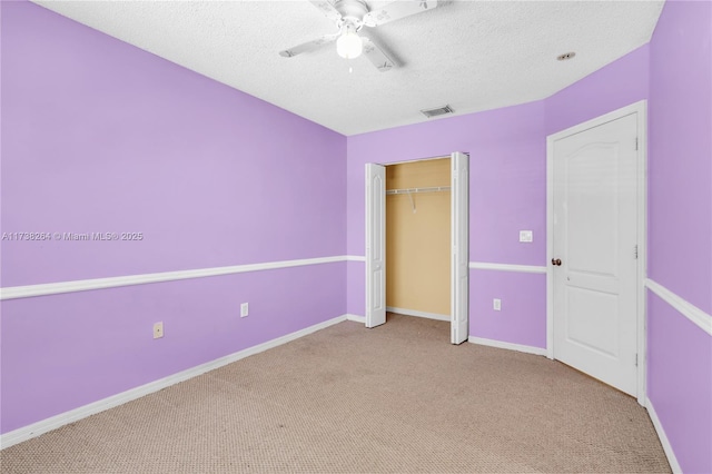 unfurnished bedroom featuring baseboards, visible vents, a ceiling fan, light colored carpet, and a textured ceiling