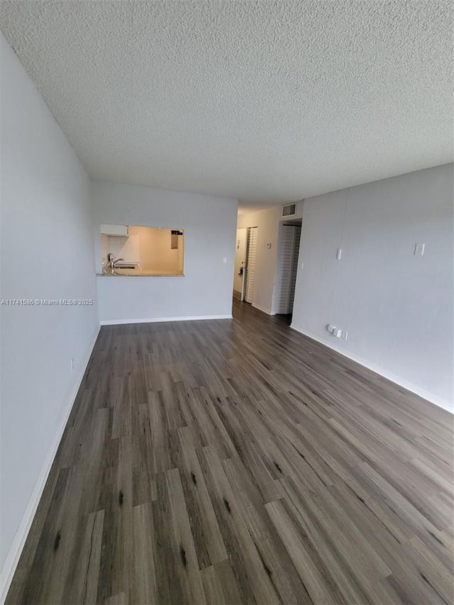 unfurnished living room featuring dark hardwood / wood-style flooring and a textured ceiling