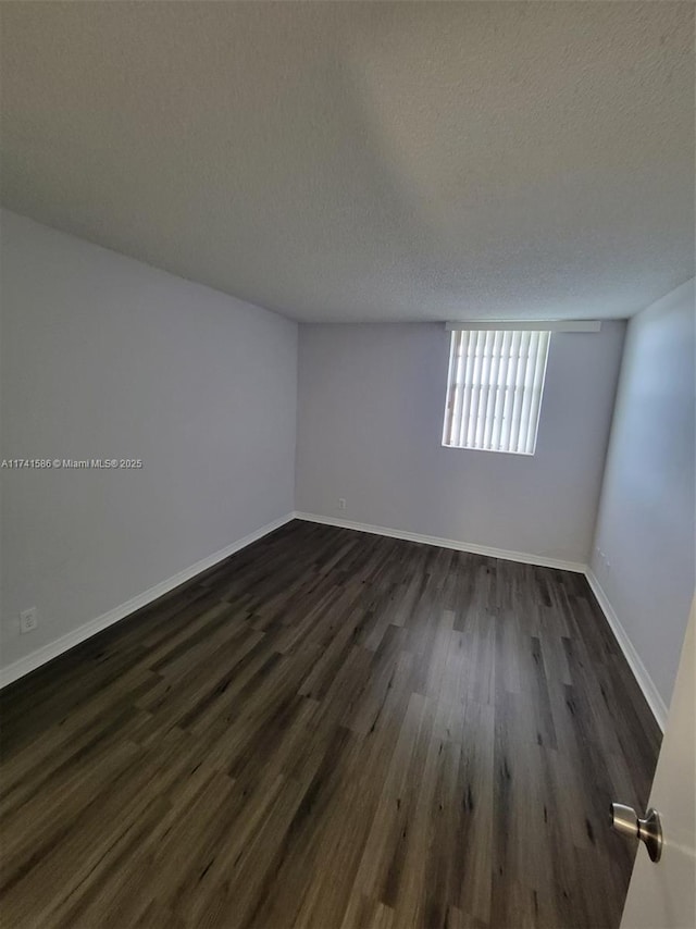 unfurnished room featuring dark wood-type flooring and a textured ceiling