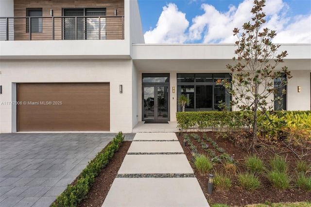 view of front of home featuring a garage, a balcony, and french doors