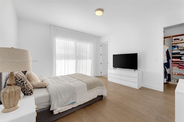 bedroom featuring a closet, a spacious closet, and light hardwood / wood-style flooring