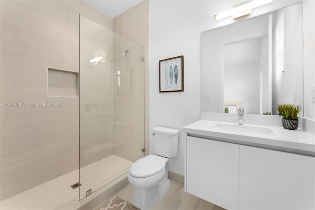 bathroom with vanity, a tile shower, tile patterned floors, and toilet