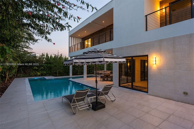 pool at dusk featuring a patio