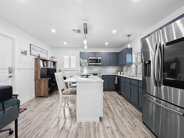 kitchen featuring a kitchen island, decorative light fixtures, sink, decorative backsplash, and stainless steel appliances