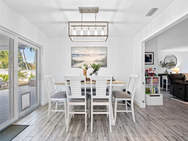 dining area with a textured ceiling and light wood-type flooring