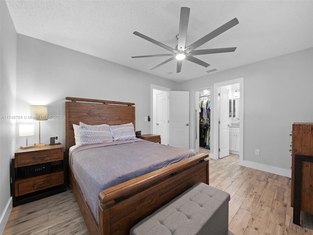 bedroom with light hardwood / wood-style flooring, ceiling fan, a textured ceiling, a walk in closet, and a closet