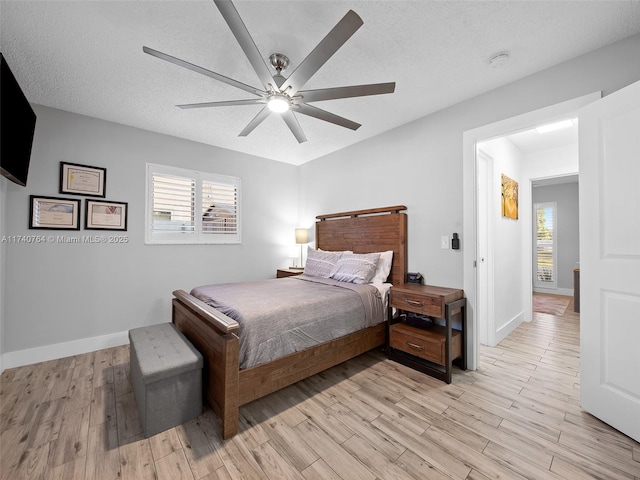 bedroom with multiple windows, light hardwood / wood-style floors, and a textured ceiling