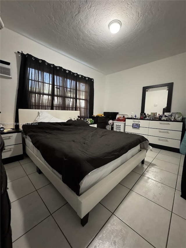 tiled bedroom featuring an AC wall unit and a textured ceiling