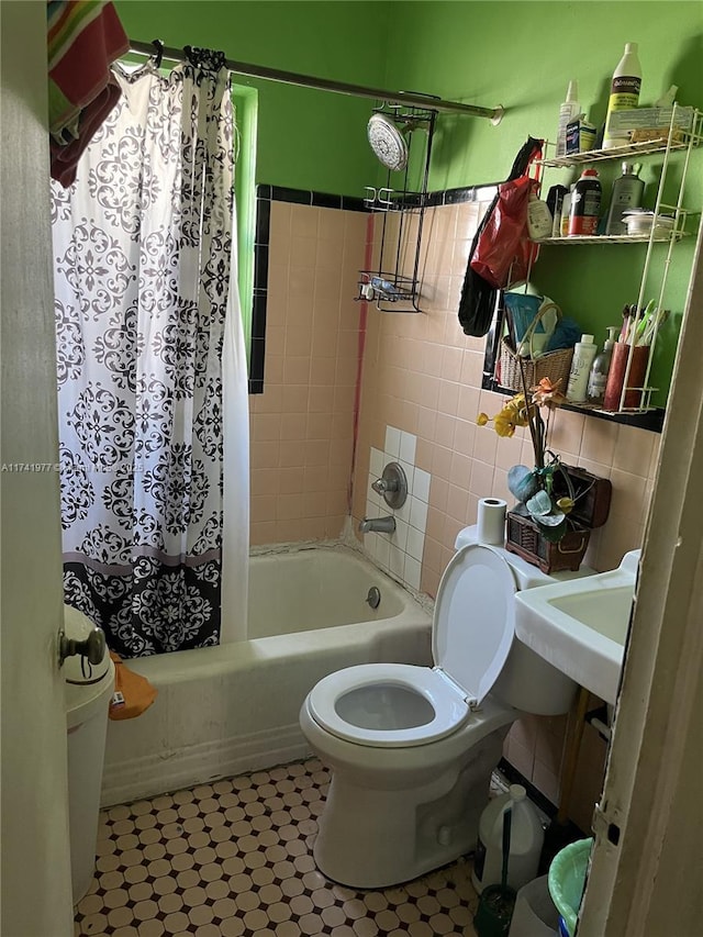 full bathroom featuring toilet, sink, shower / bath combo with shower curtain, and tile walls