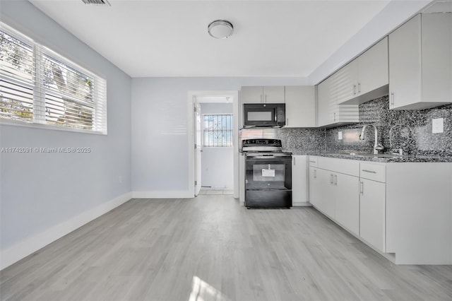 kitchen featuring sink, tasteful backsplash, stone countertops, light wood-type flooring, and black appliances