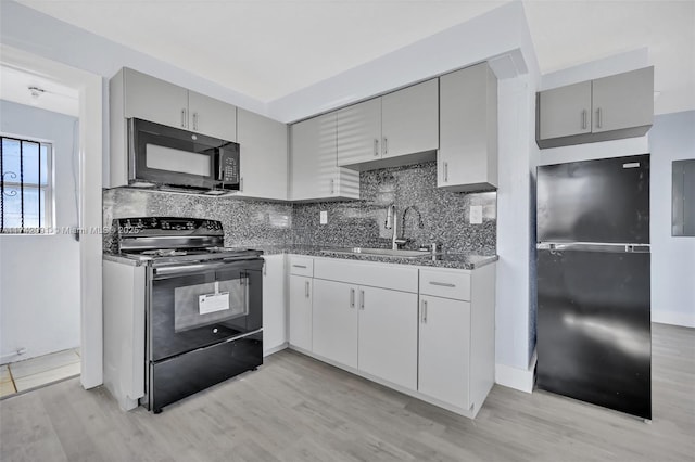 kitchen featuring sink, backsplash, light hardwood / wood-style floors, and black appliances