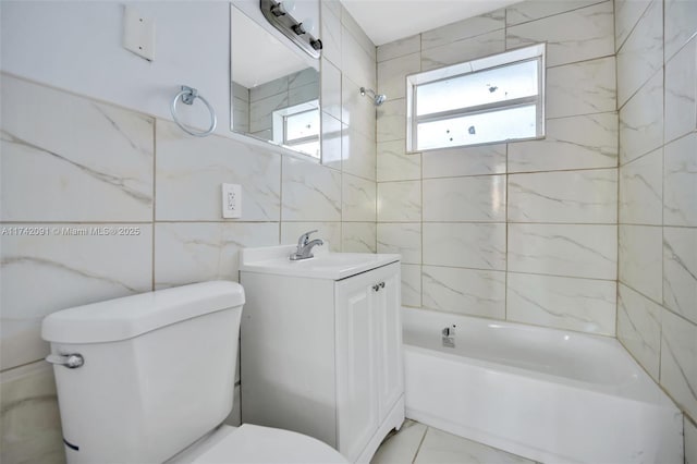 full bathroom with vanity, toilet, tiled shower / bath combo, and tile walls