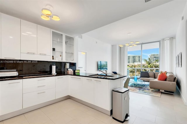 kitchen with decorative backsplash, sink, white cabinets, and kitchen peninsula