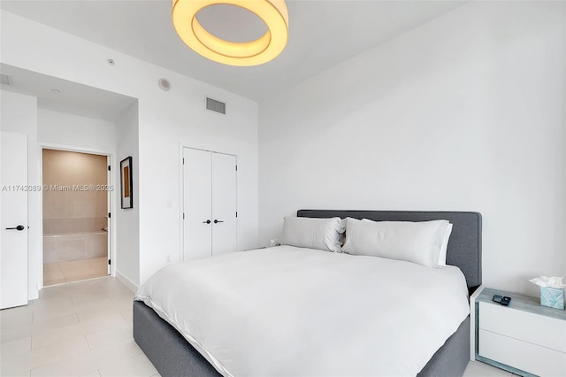 bedroom featuring light tile patterned floors, ensuite bath, and a closet