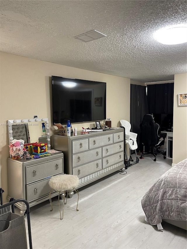 bedroom with light wood-type flooring and a textured ceiling