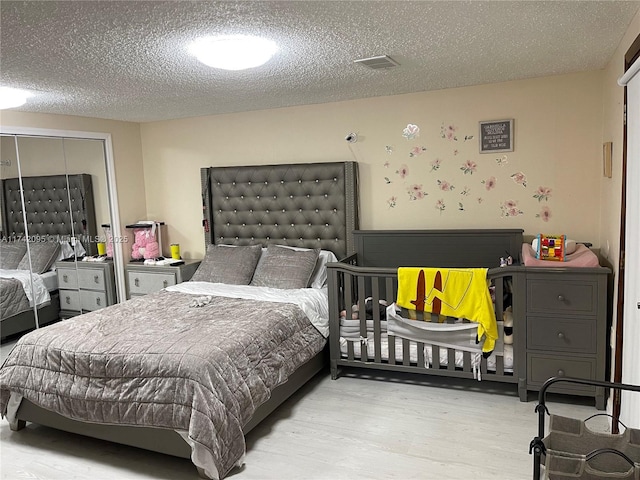 bedroom featuring a textured ceiling, a closet, and light hardwood / wood-style flooring