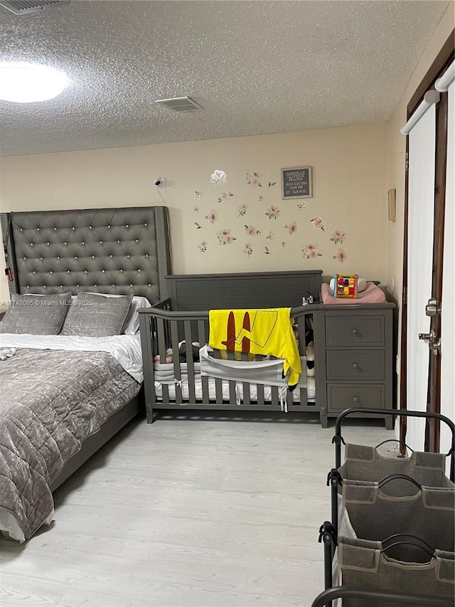 bedroom with a textured ceiling and light hardwood / wood-style floors