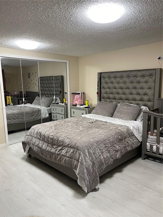 bedroom with a textured ceiling, a closet, and light hardwood / wood-style floors