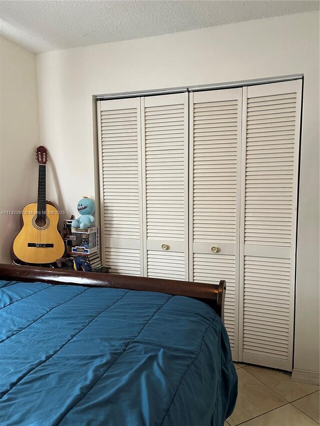 bedroom with light tile patterned floors, a textured ceiling, and a closet