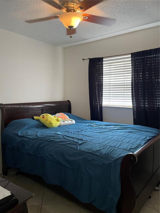 bedroom with light tile patterned floors, ceiling fan, and a textured ceiling