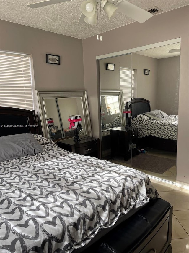 tiled bedroom with a closet, ceiling fan, and a textured ceiling