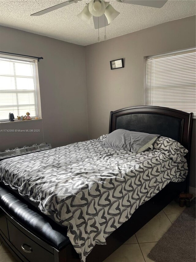 tiled bedroom with ceiling fan and a textured ceiling