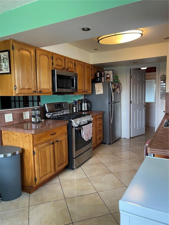 kitchen featuring tile counters, stainless steel appliances, and light tile patterned floors