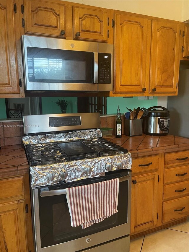 kitchen featuring light tile patterned flooring, appliances with stainless steel finishes, and tile countertops