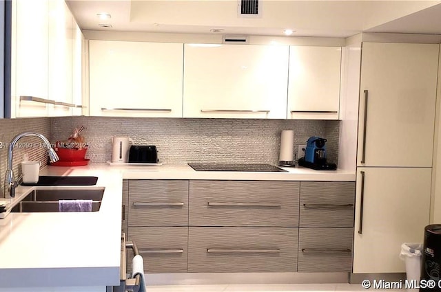 kitchen with black electric cooktop, sink, and backsplash