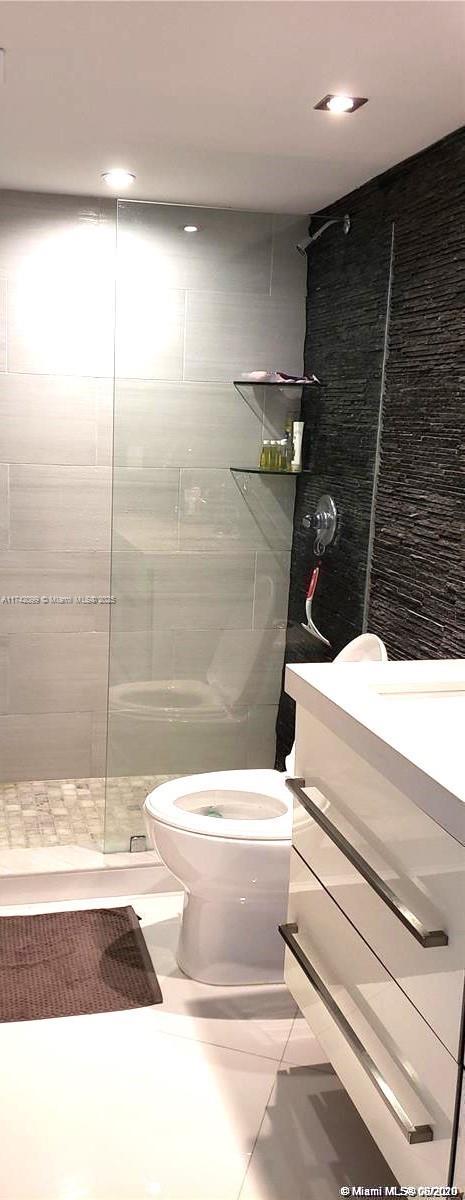 bathroom featuring tile walls, toilet, and walk in shower