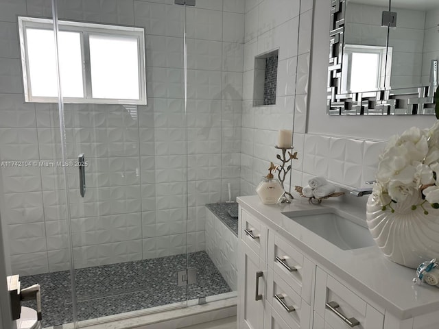 bathroom with tile walls, vanity, plenty of natural light, and a shower with shower door