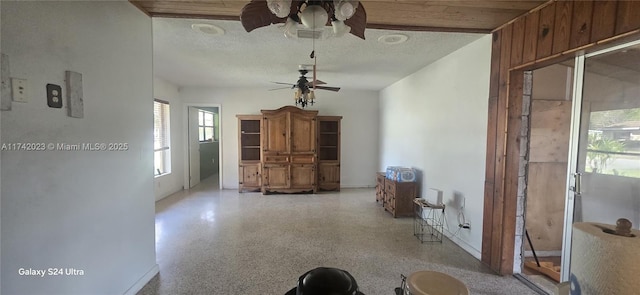 unfurnished living room with ceiling fan and a textured ceiling