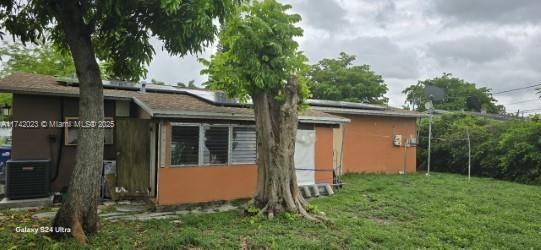 rear view of property with cooling unit and a lawn