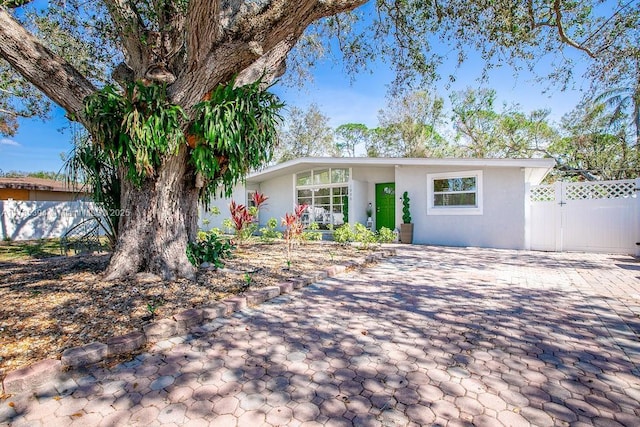 view of front of property with a gate, fence, and stucco siding