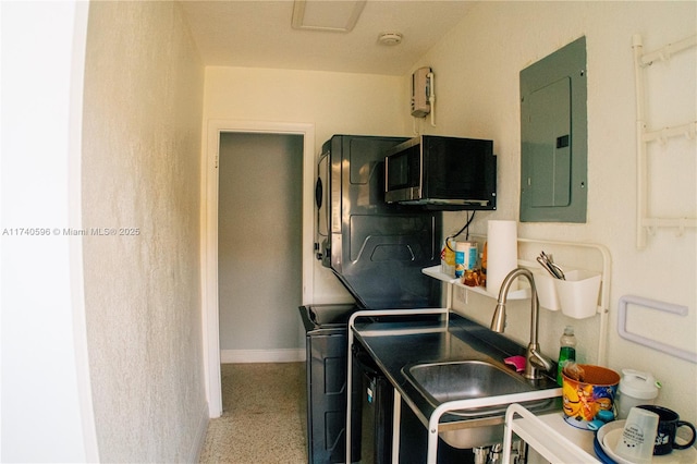 washroom featuring stacked washer and clothes dryer, sink, and electric panel