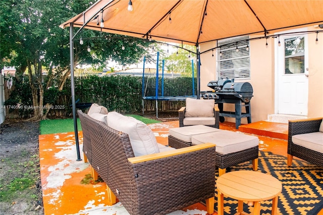 view of patio featuring a trampoline, an outdoor living space, and a gazebo