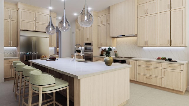 kitchen featuring a breakfast bar area, stainless steel appliances, hanging light fixtures, light brown cabinetry, and an island with sink