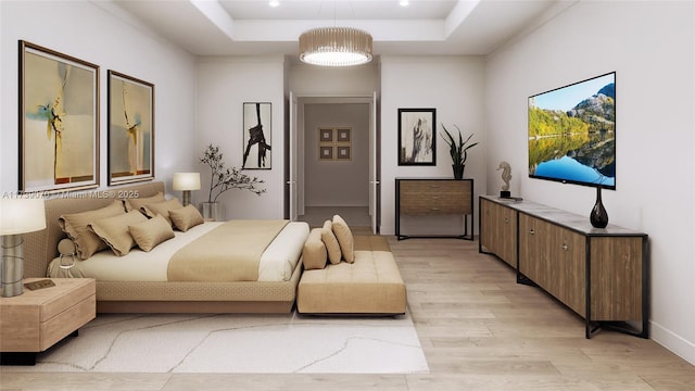 bedroom with light wood-style floors and a tray ceiling